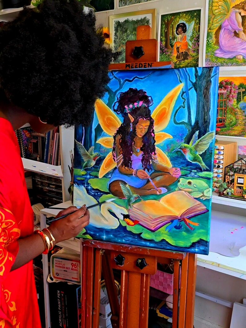May include: An artist paints a vibrant canvas depicting a fairy with golden wings, surrounded by hummingbirds and a swan. The artwork, set against a blue backdrop, is on an easel. Other paintings are visible in the background, creating an art studio setting.