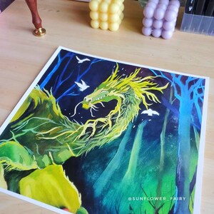 May include: A vibrant watercolor painting of a green and yellow dragon in a forest setting. The artwork features a dark blue background with white birds and trees. The artist's name, "SUNFLOWER_FAIRY," is visible in the bottom right corner.