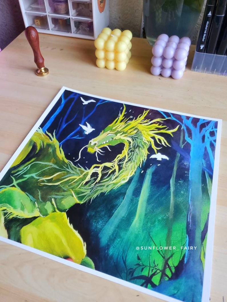 May include: A vibrant watercolor painting of a green and yellow dragon in a forest setting. The artwork features a dark blue background with white birds and trees. The artist's name, "SUNFLOWER_FAIRY," is visible in the bottom right corner.
