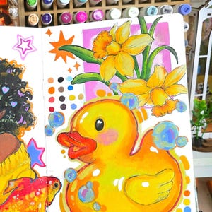 Puede incluir: Una ilustraci&oacute;n vibrante de un patito de goma amarillo con pico naranja y burbujas azules. Tambi&eacute;n se representan narcisos y un pez dorado. La obra de arte est&aacute; en una p&aacute;gina blanca, con una paleta de colores y marcadores en el fondo.