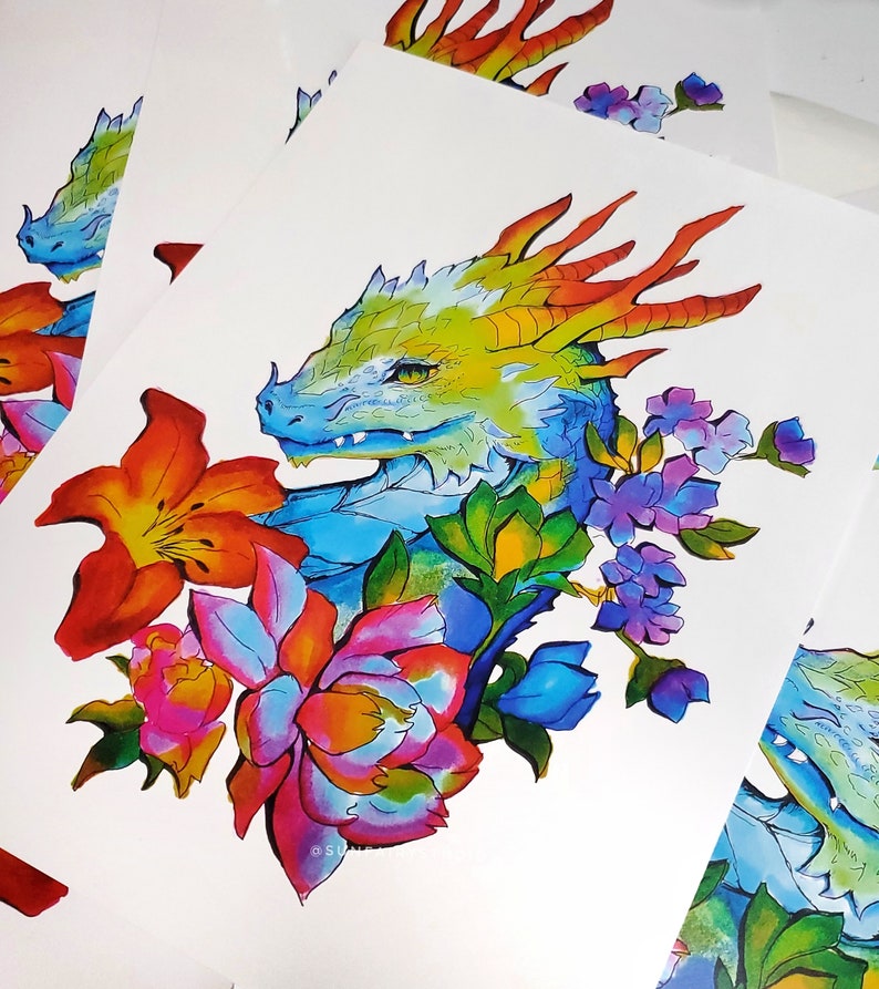 May include: Watercolor illustration of a dragon's head with vibrant colors. The dragon is surrounded by colorful flowers in shades of orange, pink, blue, and purple. The artwork is on white paper.