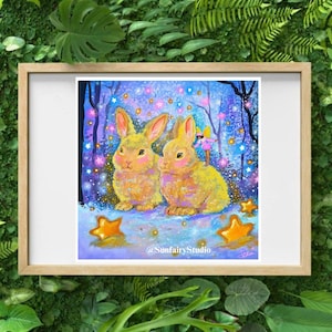 May include: A framed print featuring two yellow rabbits with pink cheeks, set in a whimsical forest scene with stars and a fairy. The artwork has a dreamy, fairytale aesthetic, with gold stars scattered around the rabbits. The artist's name is visible.