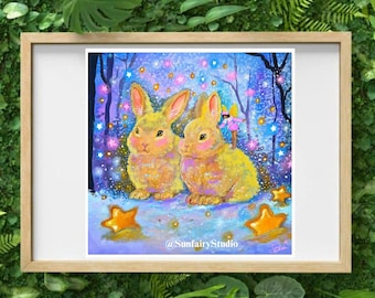 May include: A framed print featuring two yellow rabbits with pink cheeks, set in a whimsical forest scene with stars and a fairy. The artwork has a dreamy, fairytale aesthetic, with gold stars scattered around the rabbits. The artist's name is visible.
