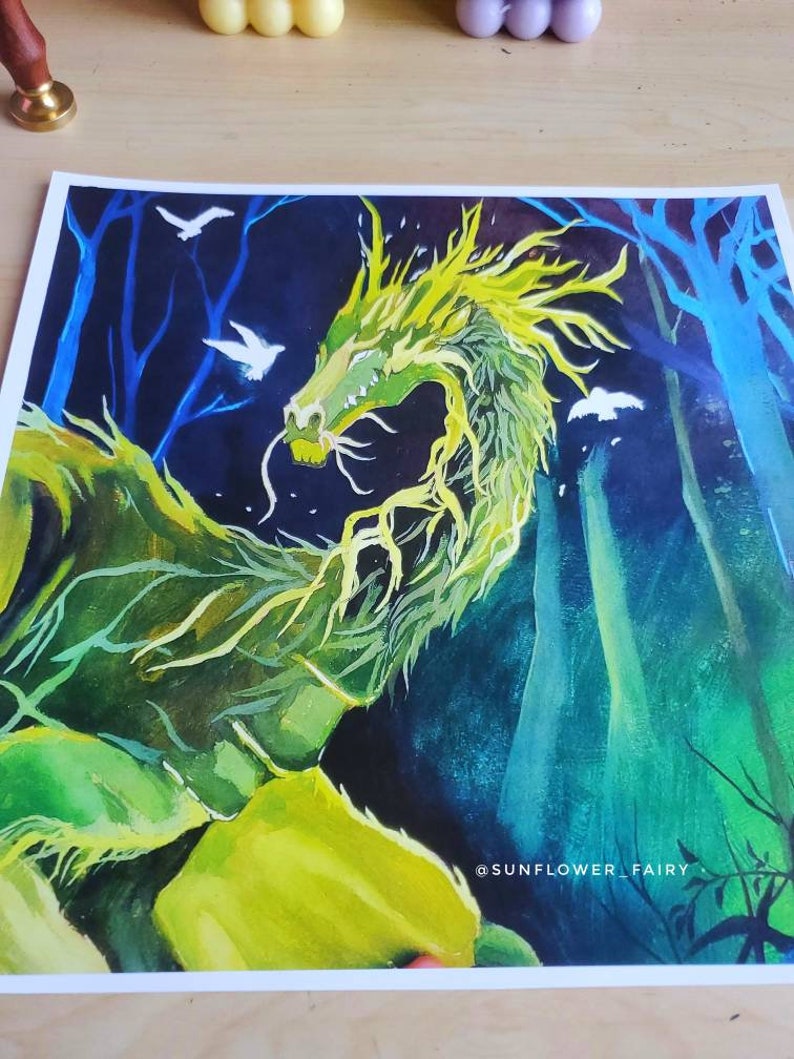 May include: A vibrant watercolor painting of a green dragon with yellow accents, set against a dark blue forest background. White birds fly in the sky. The artist's name, "SUNFLOWER_FAIRY," is visible in the lower right corner.