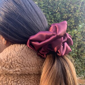 Könnte beinhalten: Ein burgunderfarbener Satin-Haargummi.