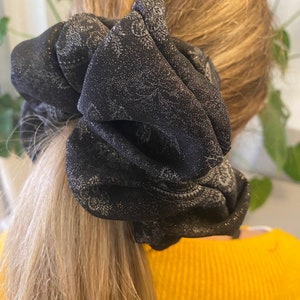 May include: A black and silver patterned scrunchie with a sparkly finish.