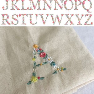 Puede incluir: Primer plano de la letra A bordada con flores de colores sobre una tela beige. La tela est&aacute; doblada y el texto "font 4" es visible en la parte inferior de la imagen.