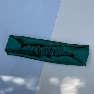 May include: A dark green satin headband with a gathered centre.