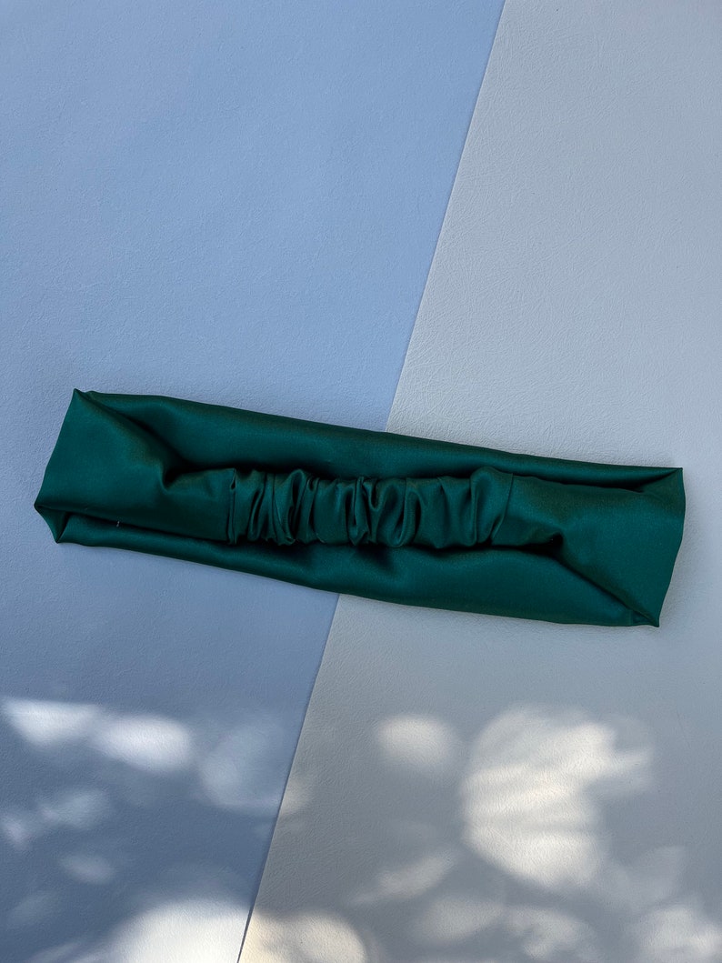 May include: A dark green satin headband with a gathered centre.