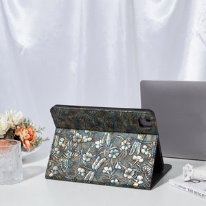 May include: A black leather iPad case with a floral and dragonfly design in shades of gold, green, and blue.