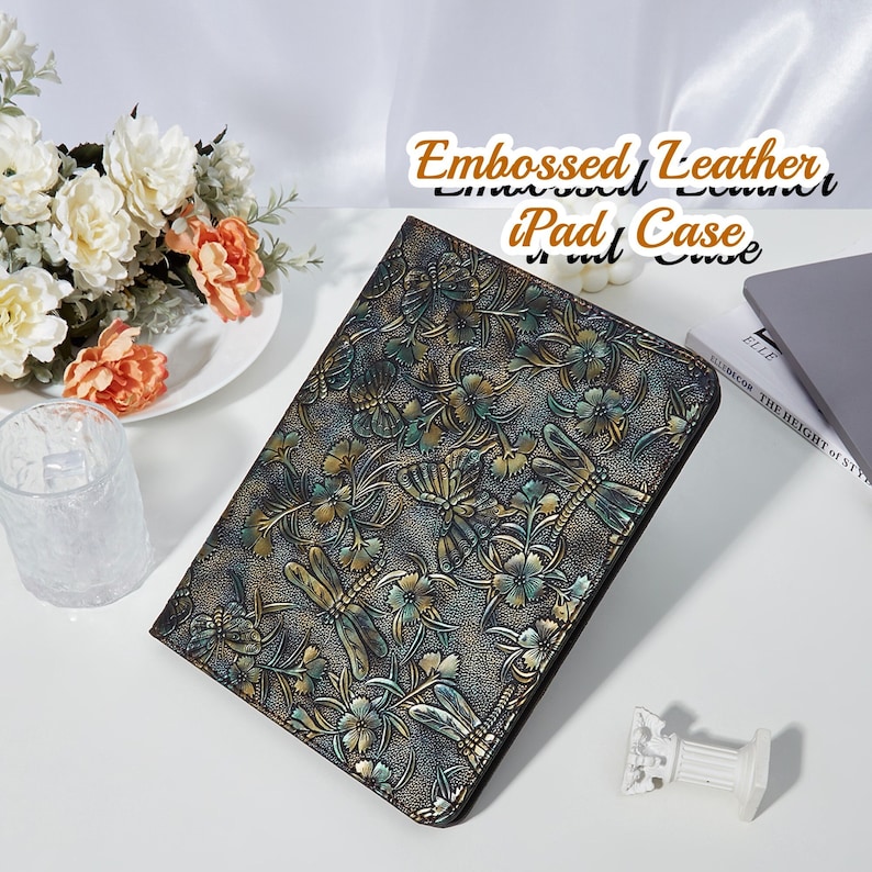 May include: Embossed leather iPad case with a floral and dragonfly design. The case is dark brown with gold accents.