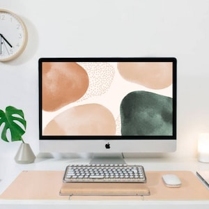 May include: A white desktop computer with a light brown and green abstract design on the screen. The computer is on a white desk with a white keyboard, a light brown mouse pad, a white mouse, a white phone, a green plant, and a white lamp.