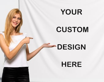 Könnte beinhalten: Eine Frau zeigt auf ein weißes Banner mit dem schwarzen Text "YOUR CUSTOM DESIGN HERE". Sie trägt ein weißes Oberteil und eine schwarze Hose. Das Banner steht auf einem Ständer vor einer weißen Wand.