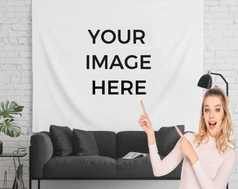 May include: A white tapestry with the text "YOUR IMAGE HERE" hanging on a white brick wall. A person is pointing to the tapestry. A black couch is in front of the tapestry.