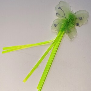 May include: A fairy wand featuring a green butterfly-shaped top with silver glitter and a fluffy green center. The wand has a long, bright green handle with matching streamers, perfect for imaginative play.