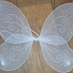 May include: White fairy wings with a sparkly, swirl design. The wings are made of a sheer, delicate fabric.