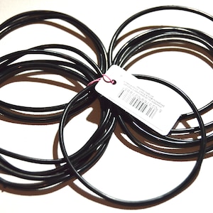 May include: A set of black rubber bracelets, stacked and tangled together. A white tag with a barcode and text is attached to the bracelets.