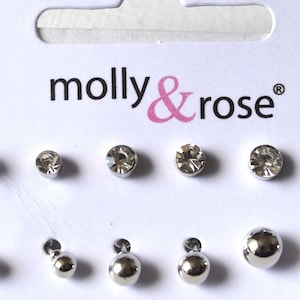 May include: A set of 10 silver stud earrings featuring clear crystal and silver ball designs. The earrings are presented on a white card with the brand name "molly & rose" printed in pink.
