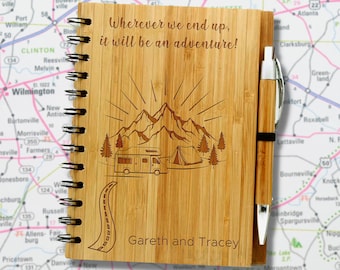May include: A wooden journal with a spiral binding and a pen. The journal has a laser-engraved design of mountains, a camper van, and a tent. The text "Wherever we end up, it will be an adventure!" is engraved on the front cover. The names "Gareth and Tracey" are also engraved on the front cover.