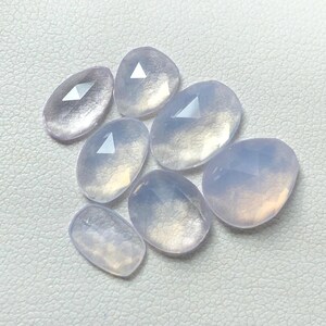 Könnte beinhalten: Sieben durchscheinende, helllila, oval geformte Edelsteine mit facettierten Oberflächen.