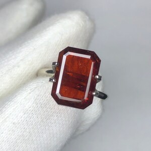 Peut inclure: Une bague en argent avec une grande pierre précieuse rectangulaire rouge foncé.