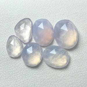 Puede incluir: Seis piedras preciosas facetadas, translúcidas, de color púrpura claro de diferentes tamaños.