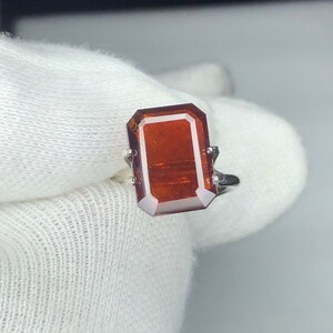 Peut inclure: Une bague en argent avec une grande pierre précieuse rectangulaire rouge foncé.