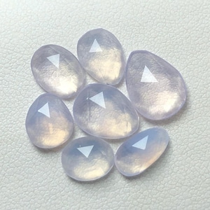 Puede incluir: Siete piedras preciosas iridiscentes, de color púrpura claro, facetadas, en forma de lágrima.