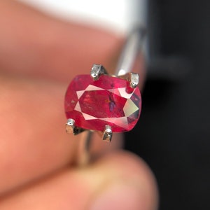 Op de afbeelding: Een close-up van een rode ovale edelsteen gezet in een zilveren ring.