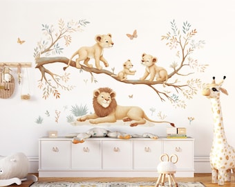 May include: A nursery wall decal set featuring a family of lions and a giraffe. The decals are illustrated in a watercolor style with a light brown, beige, and cream color palette. The lions are depicted on a branch with leaves, while the giraffe stands on the floor.