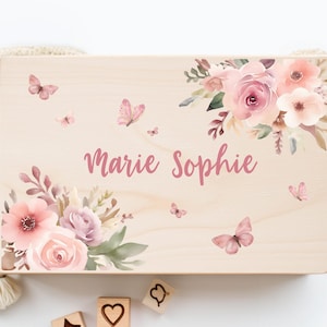 Könnte beinhalten: Eine Holzkiste mit einem Blumendesign und dem Namen "Marie Sophie" darauf. Die Kiste ist mit rosa und weißen Blumen und Schmetterlingen verziert.