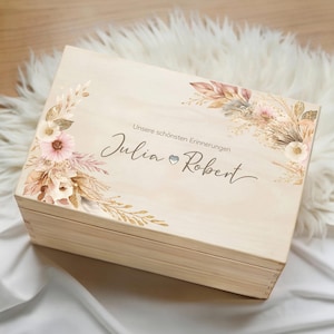 Op de afbeelding: Een witte keramische mok met een zwart handvat en de tekst "But First, Coffee" in een zwarte, vette letter. De mok staat op een houten oppervlak.