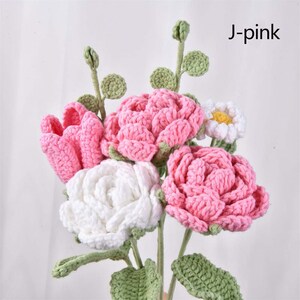 May include: A bouquet of crocheted flowers in pink and white. The bouquet includes roses, tulips, and daisies. The flowers are arranged in a vase and have green crocheted leaves.