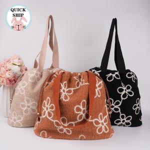 May include: Three tote bags with different floral patterns. The bags are made of a soft, fuzzy material and have a drawstring closure. The bags are in beige, brown, and black.