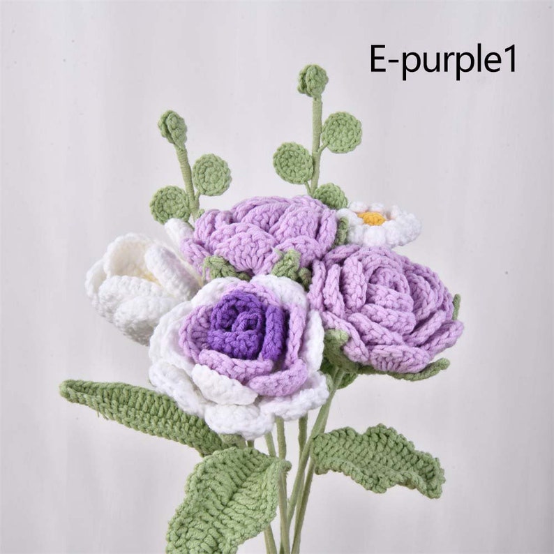 May include: A bouquet of crocheted flowers in shades of white, purple, and light pink. The flowers are arranged in a vase and have green crocheted leaves.