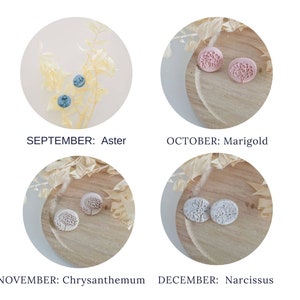 May include: Four pairs of earrings, each pair displayed on a small wooden plate with dried flowers. The earrings are made of polymer clay and feature a floral design. The colors of the earrings are blue, pink, white, and light gray.