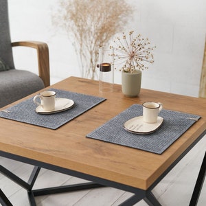 A cozy living room setting with a wooden table featuring grey textured placemats and white ceramic plates.