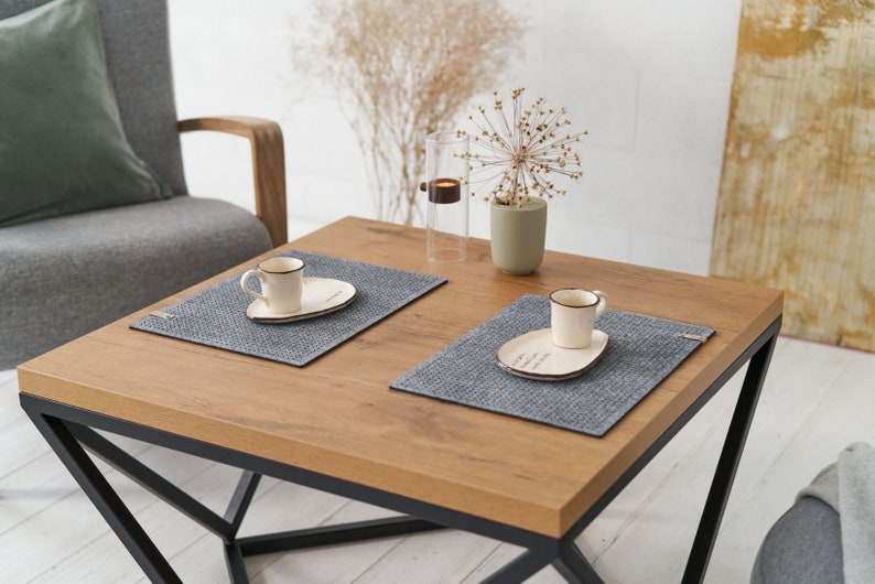 A cozy living room setting with a wooden table featuring grey textured placemats and white ceramic plates.