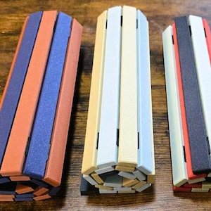 May include: Three colorful, cylindrical objects made of wooden slats. One is orange, blue, and brown. Another is yellow, white, and blue. The last is red, black, and white. They appear to be decorative or functional.
