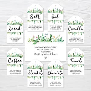 May include: A collection of white gift tags with floral designs and various labels, including "Salt," "Oil," "Bread," "Candle," "Coffee," "Towel," "Blanket," and "Chocolate." Each tag has a unique message. A central card reads "May those who live here and those who visit know only blessing, peace & love."