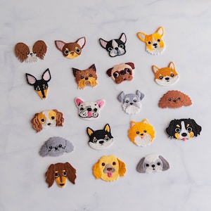 May include: A collection of 18 embroidered iron-on patches featuring various dog breeds. The patches are colourful and feature different dog breeds, including a chihuahua, a pug, a bulldog, a dachshund, a poodle, a schnauzer, a golden retriever, a labrador, a husky, a corgi, a terrier, a beagle, a basset hound, a sheepdog, a border collie, a german shepherd, a rottweiler, and a pit bull.