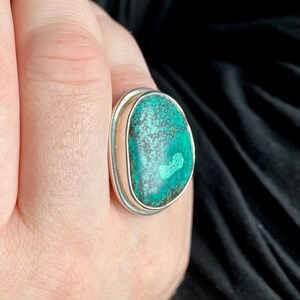 May include: A silver ring with a large oval turquoise stone set in a bezel setting.