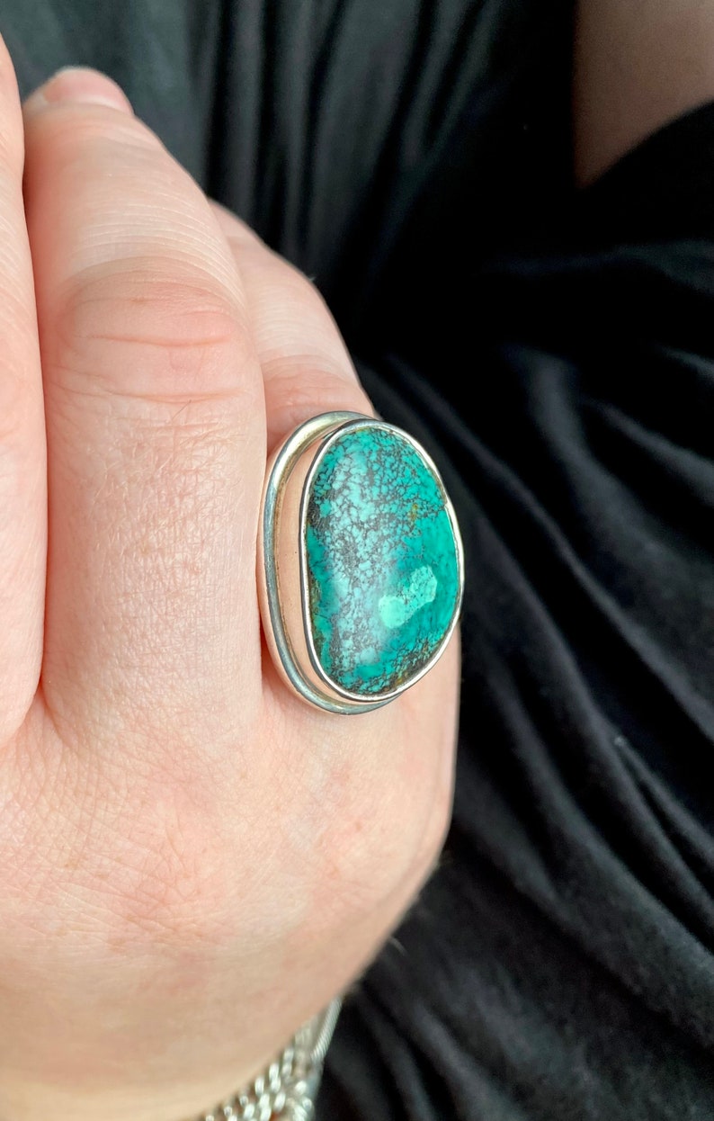 May include: A silver ring with a large oval turquoise stone set in a bezel setting.