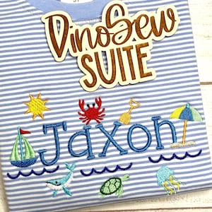 May include: Blue and white striped t-shirt with embroidered beach-themed designs, including a sailboat, sun, crab, and the name "Jaxon" in blue. A wooden cutout reads "DinoSew SUITE".