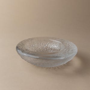 Könnte beinhalten: Ein Aschenbecher aus klarem Glas mit strukturierter Oberfläche.