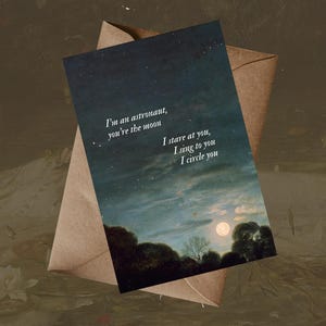 May include: A greeting card with a night sky scene, a full moon, and dark trees. The card has the text "I'm an astronaut, you're the moon. I stare at you, I sing to you, I circle you." It is inside a brown envelope.