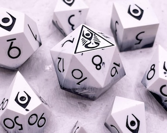 May include: A set of eight white and black dice with a unique eye symbol on each face. The dice are made of a marbled material with a black and white swirl pattern.