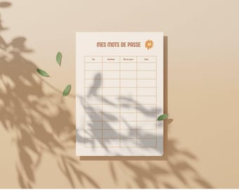 Peut inclure: Un carnet de mots de passe crème avec les mots "MES MOTS DE PASSE" en marron. Le carnet comporte une grille de cases pour saisir des informations. Un petit graphisme de fleur orange est à côté du texte. Le fond est marron clair avec des ombres de feuilles.