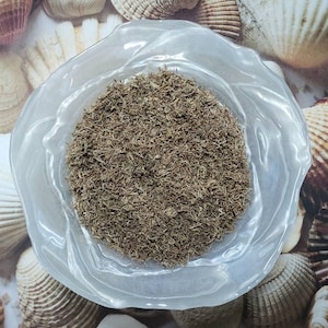 May include: A clear glass bowl filled with dried herbs, the herbs are a light brown color and have a fine texture.