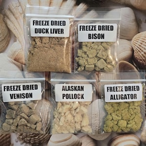 Puede incluir: Cinco bolsas de plástico transparente resellables con premios liofilizados para mascotas. Las etiquetas dicen: FREEZE DRIED DUCK LIVER, BISON, VENISON, ALASKAN POLLOCK y ALLIGATOR. El contenido varía en color y textura.